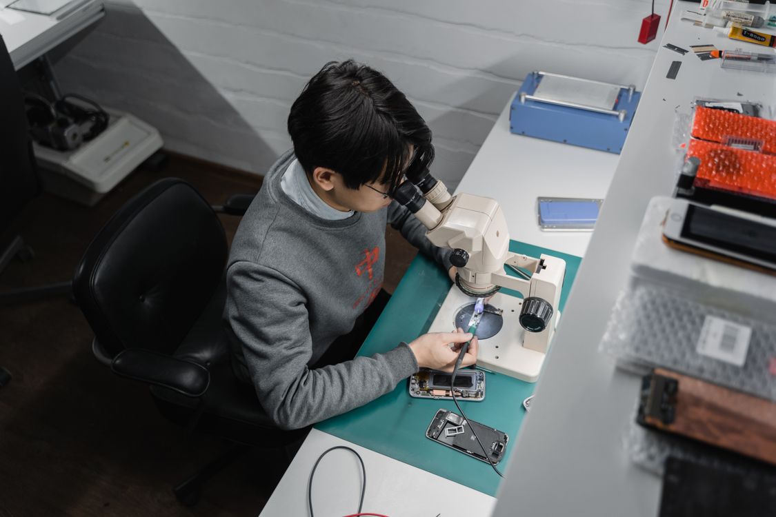 Técnico examinando um celular em uma bancada de reparo